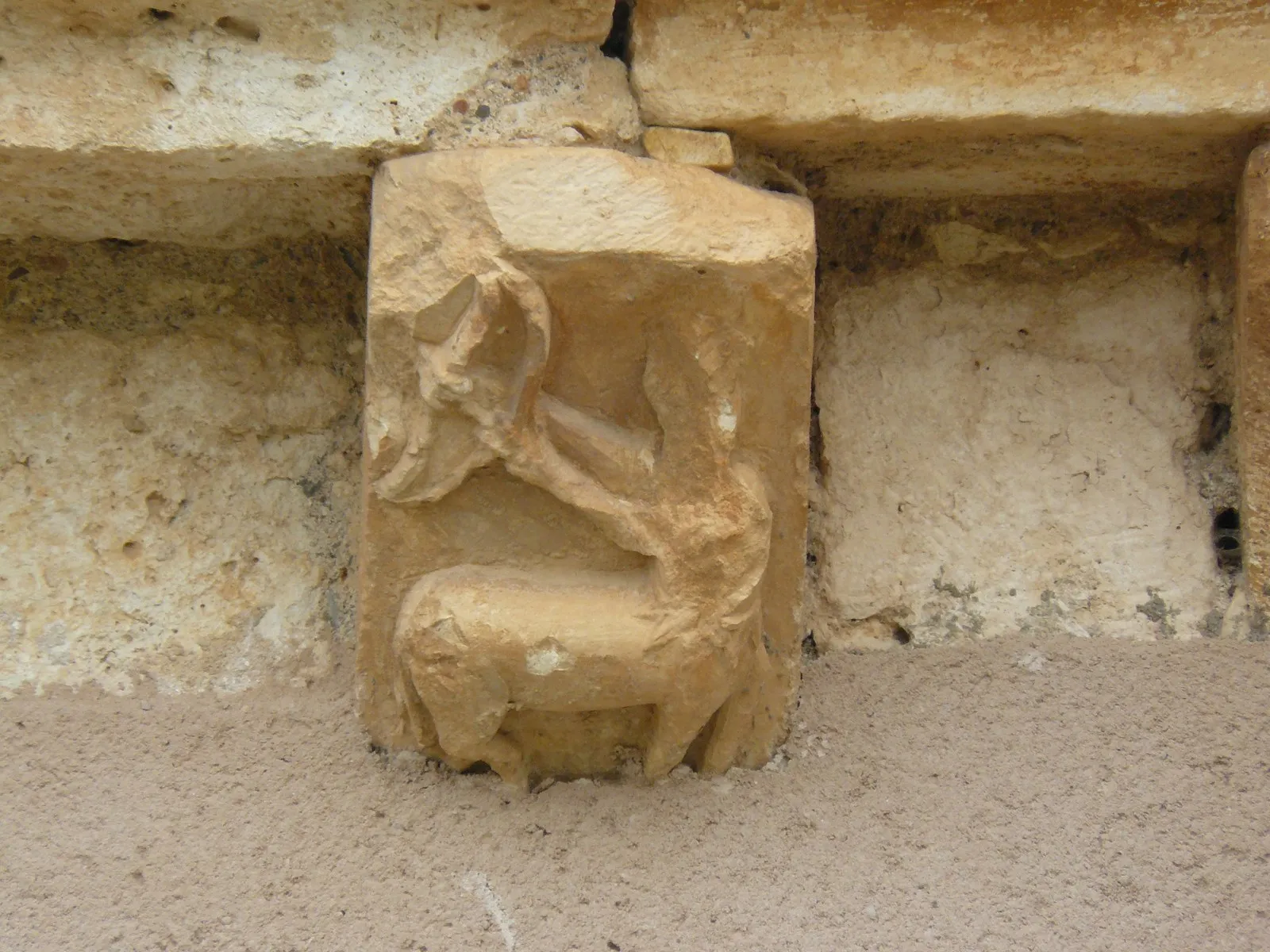 Un canecillo de piedra con un centauro que tensa un arco, bajo la cornisa de la iglesia