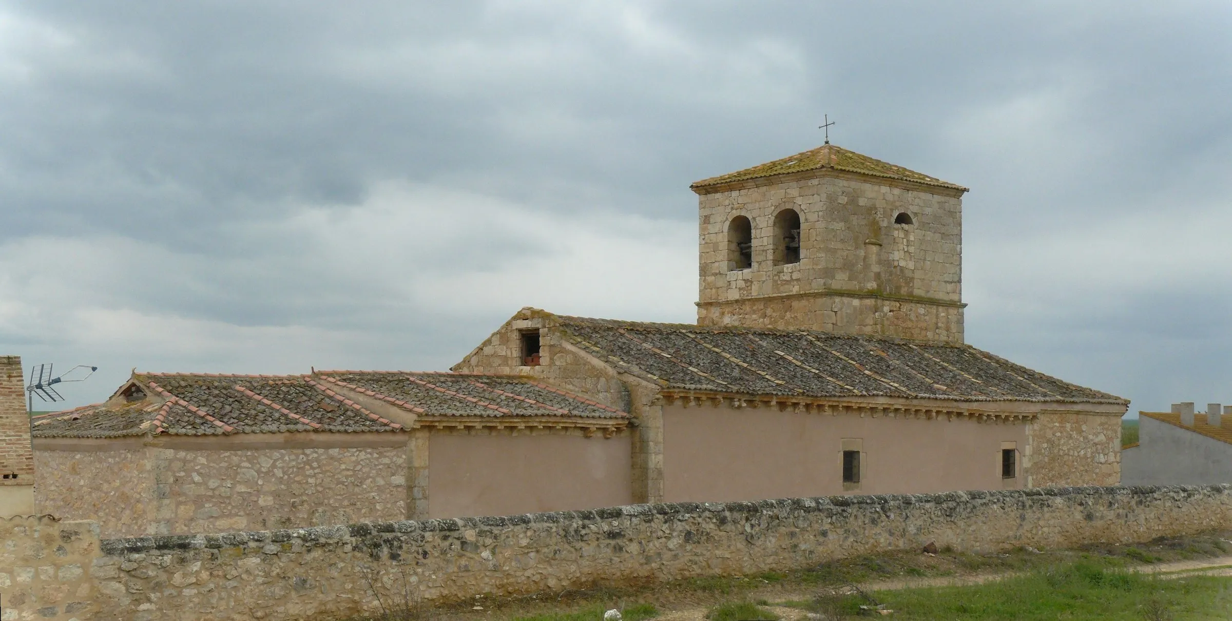La iglesia de Nuestra Señora de la Asunción de Aldealengua vista de lado, con su torre de piedra y la tapia que la rodea
