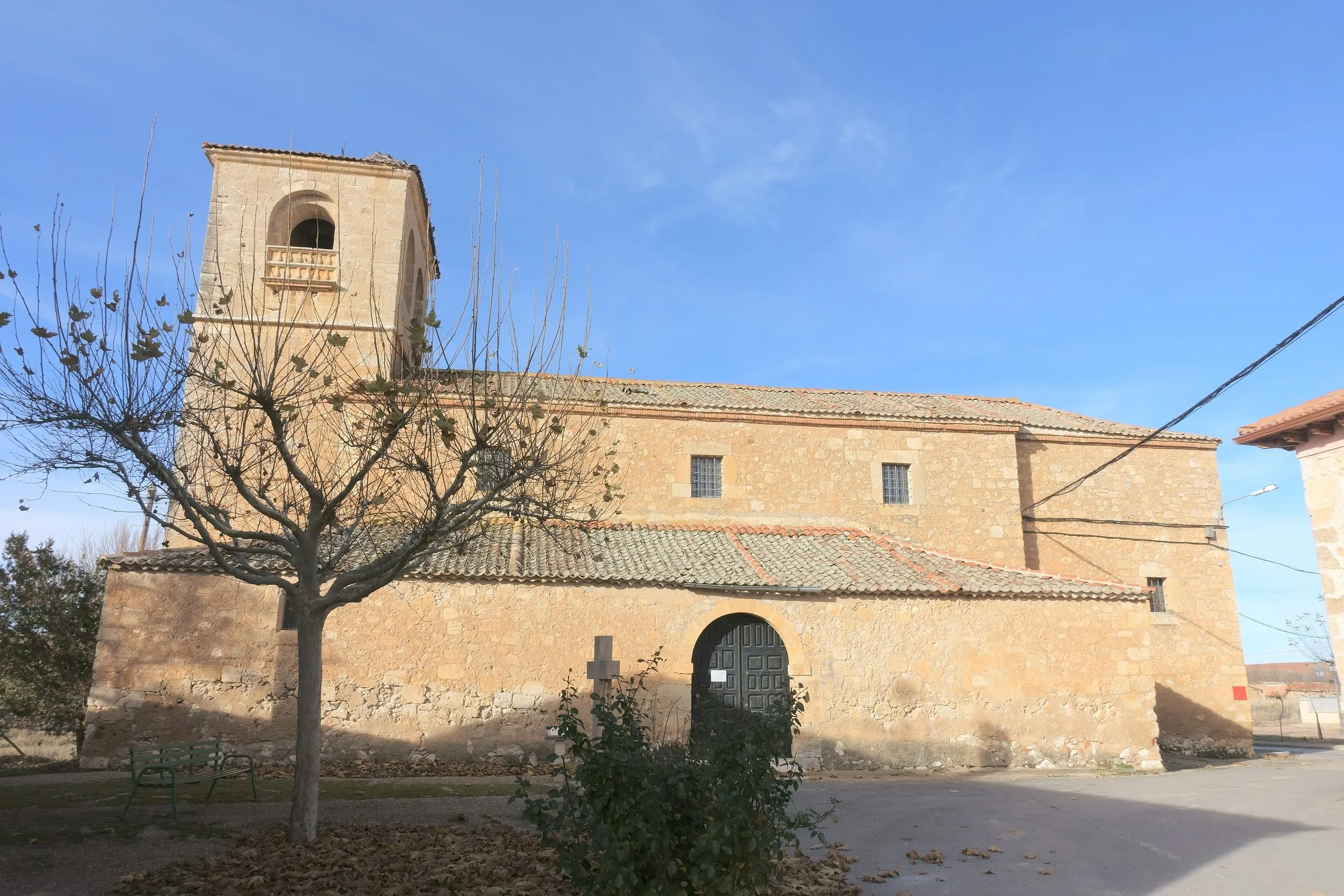 La iglesia de San Bartolomé de Riaguas, de sillería dorada, con la torre a los pies y la portada de medio punto en el muro sur