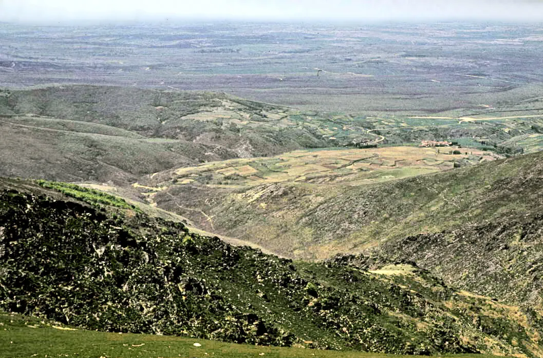 Ladera de monte bajo que desciende desde el puerto del Cervunal hacia el valle, con la llanura abierta al fondo, en mayo de 1974