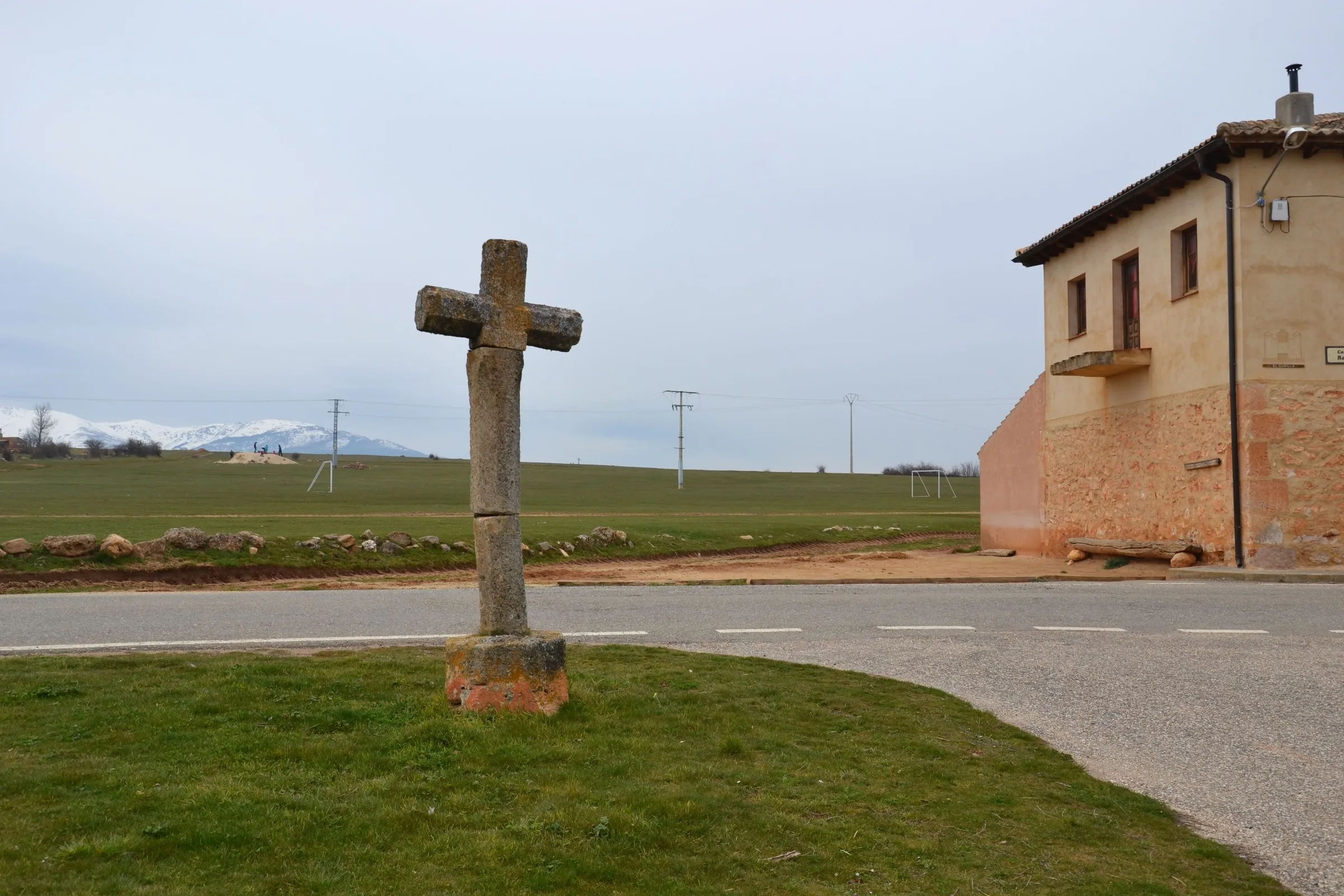 El crucero de piedra a la entrada de Valvieja, con la sierra nevada al fondo